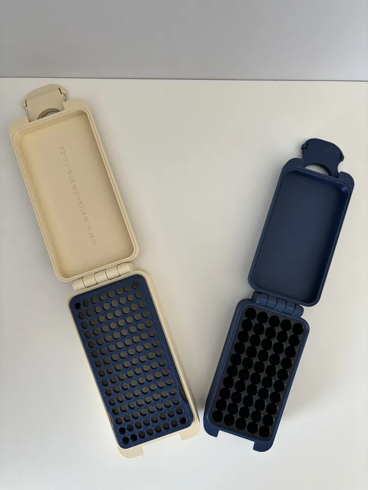 Two ammo boxes open, showing printed inserts with round holes