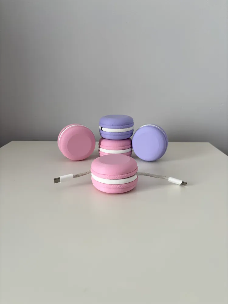 Pink and lilac macaron-shaped cable winders, one wrapped with a USB-C cable