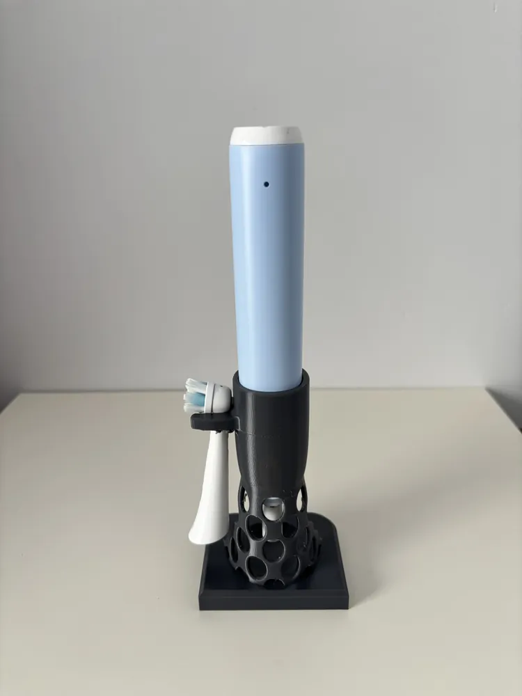 Black stand holding an electric toothbrush and spare brush heads